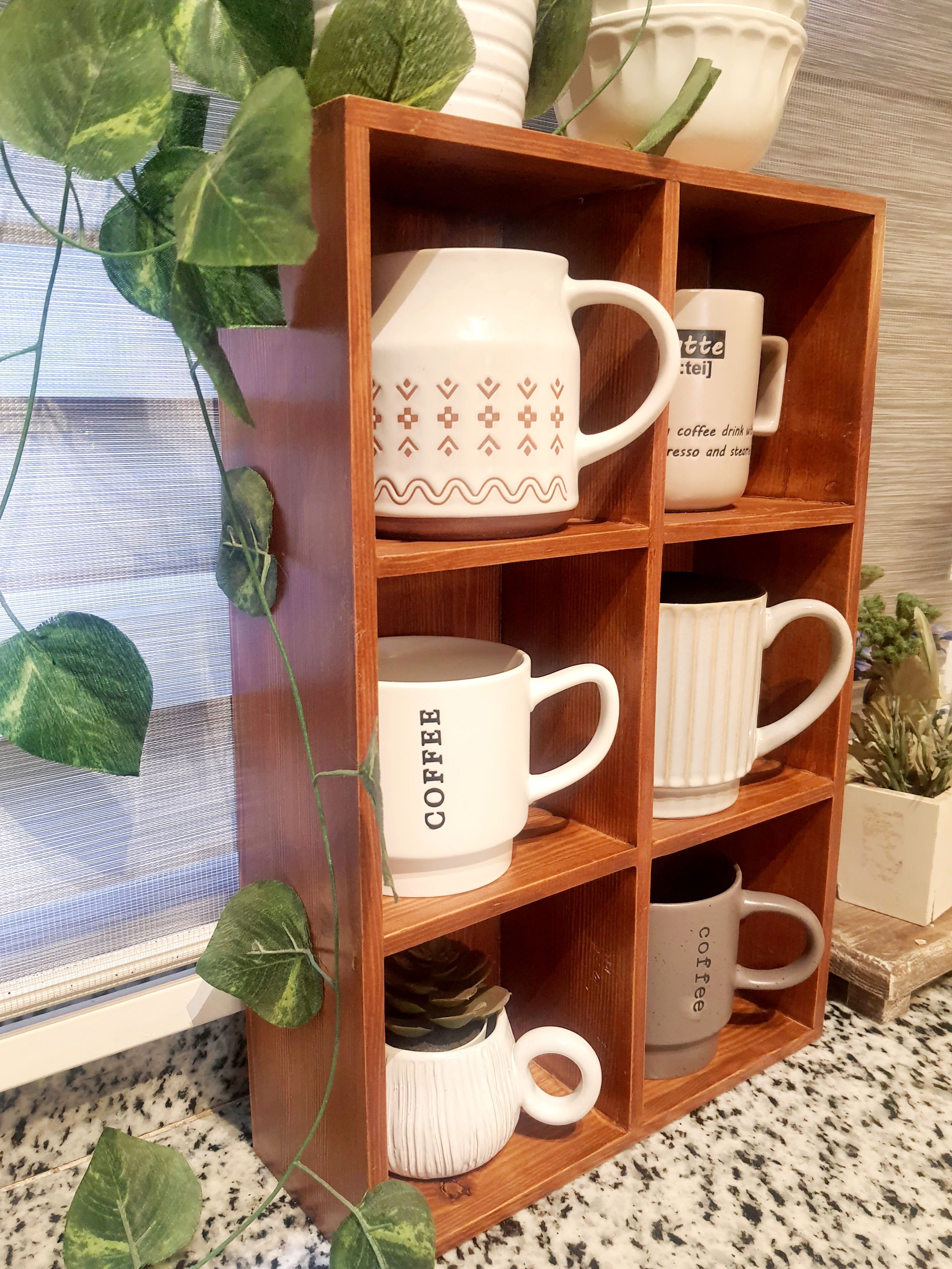 Wooden shelf with various mugs and a plant in the background
