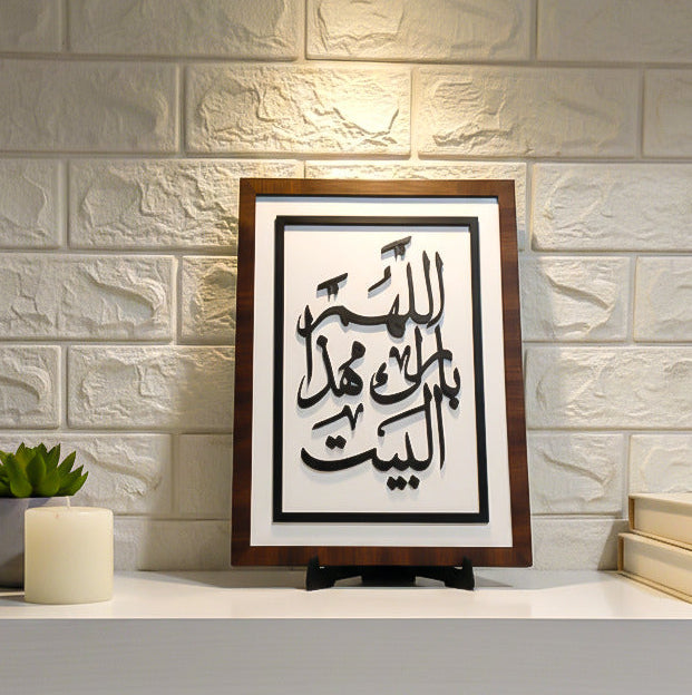 Framed calligraphy artwork on a shelf with a light gray brick wall background