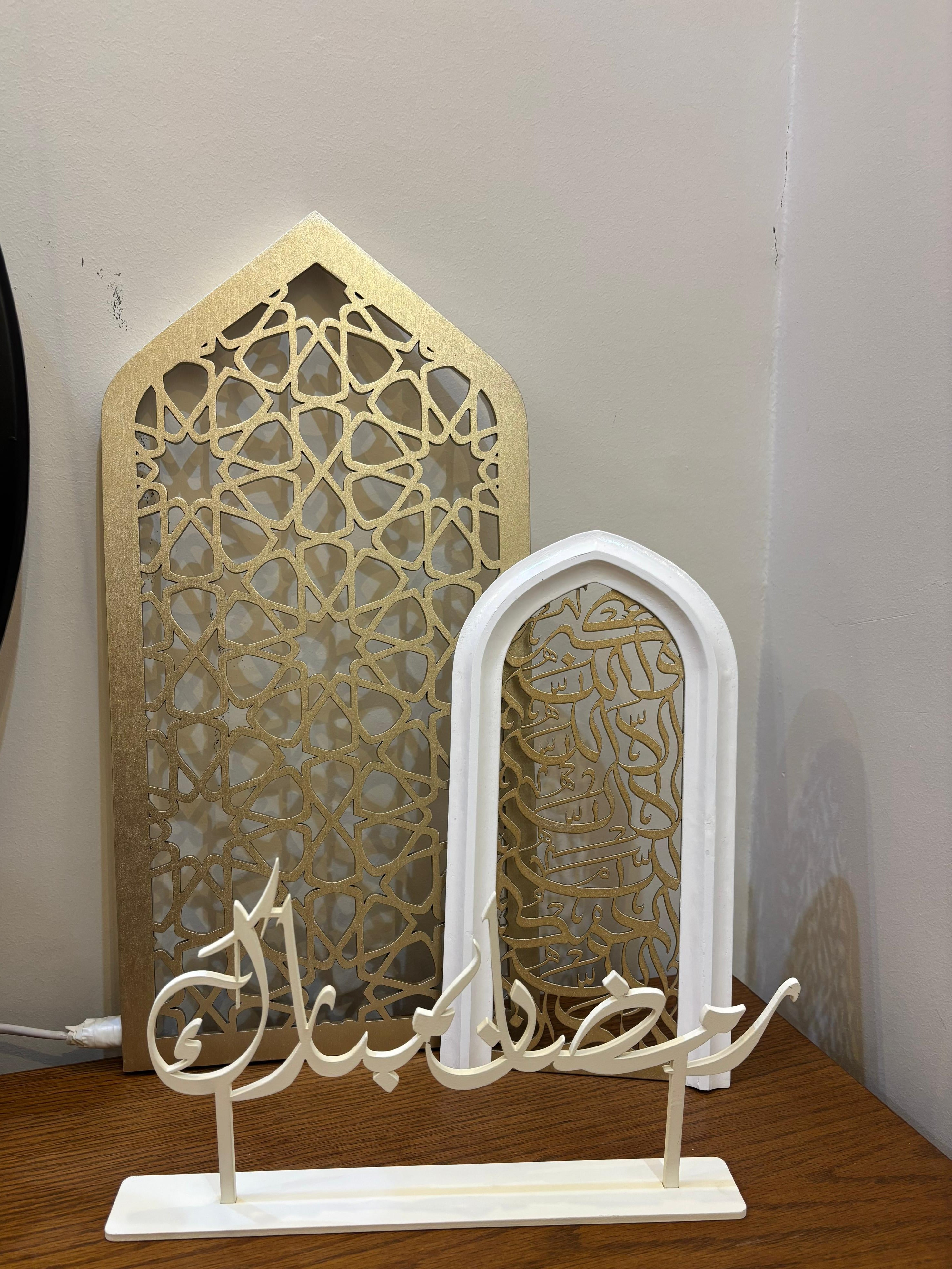 Decorative Arabic calligraphy piece on a stand with intricate geometric patterns in the background.