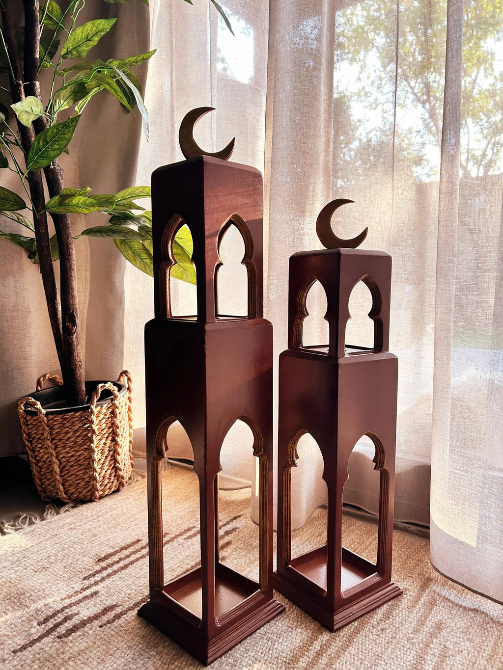 Two wooden lanterns with crescent moon designs on a carpeted floor.