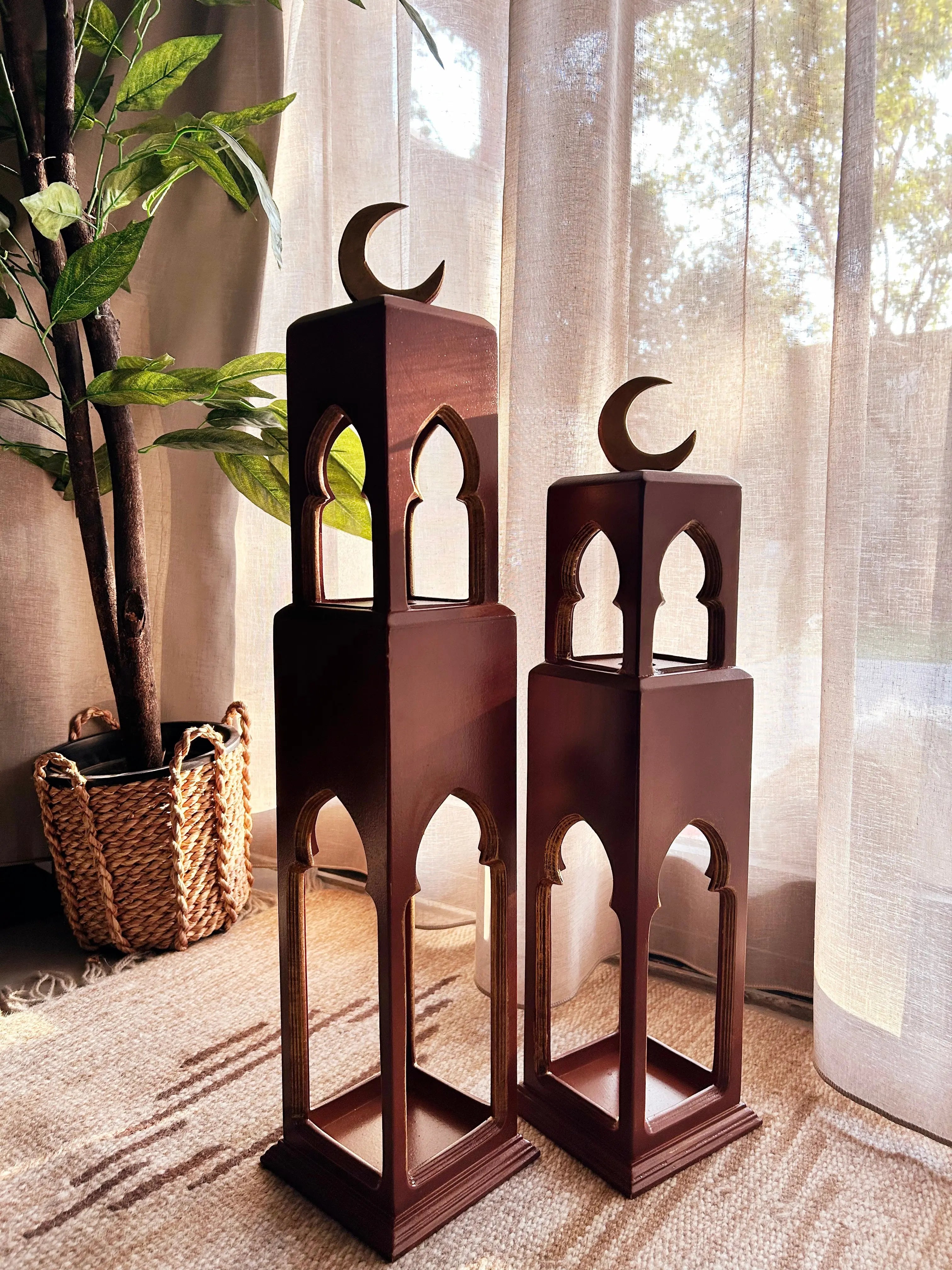 Two wooden lanterns with crescent moon designs on a carpeted floor.