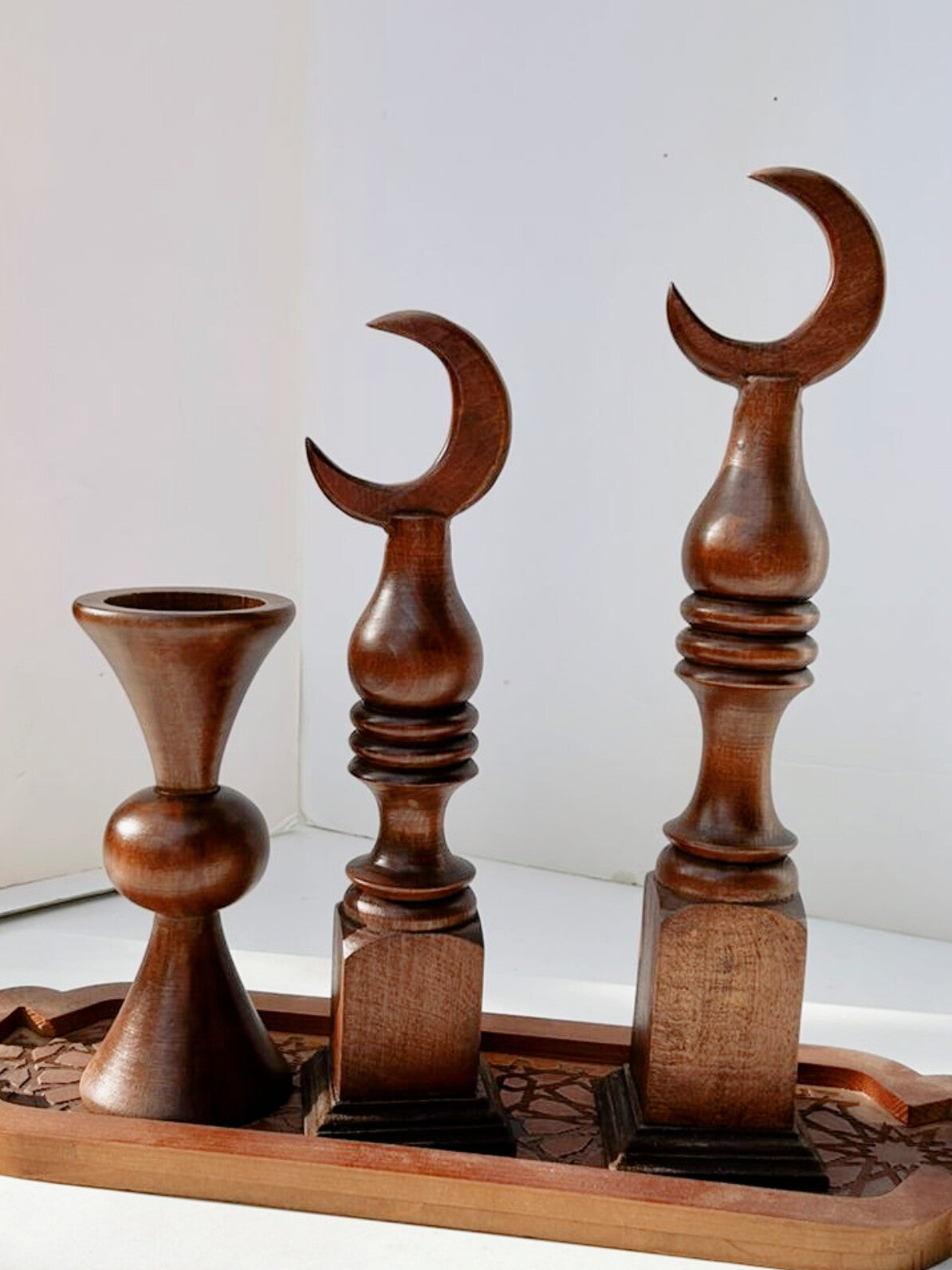 Wooden candle holders with crescent moon design on a white background