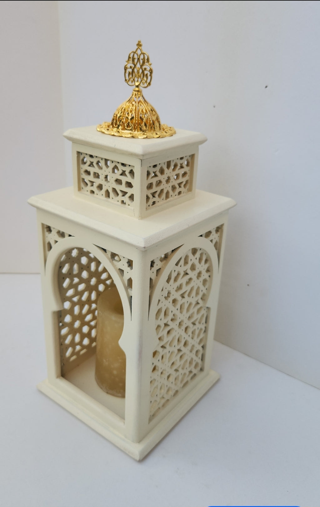 Decorative lantern with intricate cut-out design and gold top on a white background