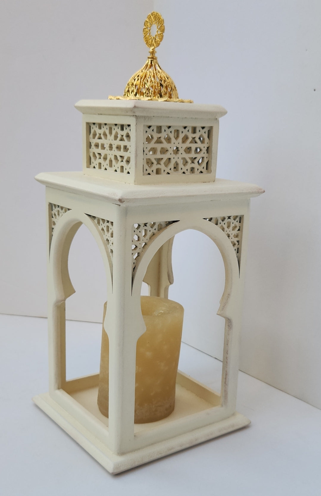 Decorative white lantern with a gold top and candle inside on a white background