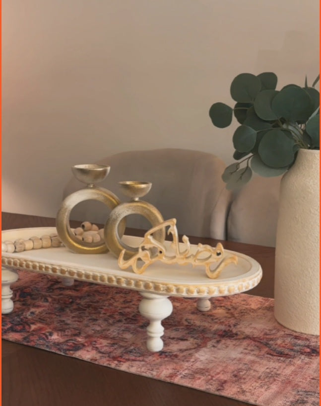 Decorative items on a marble surface with a vase of greenery.