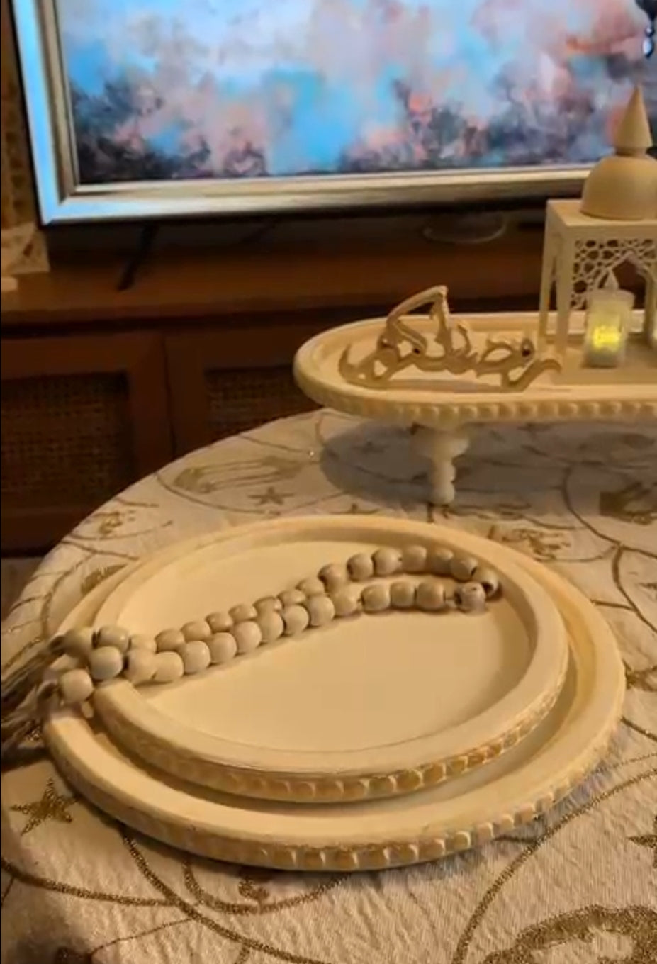 Decorative trays with beads on a table in front of a television.