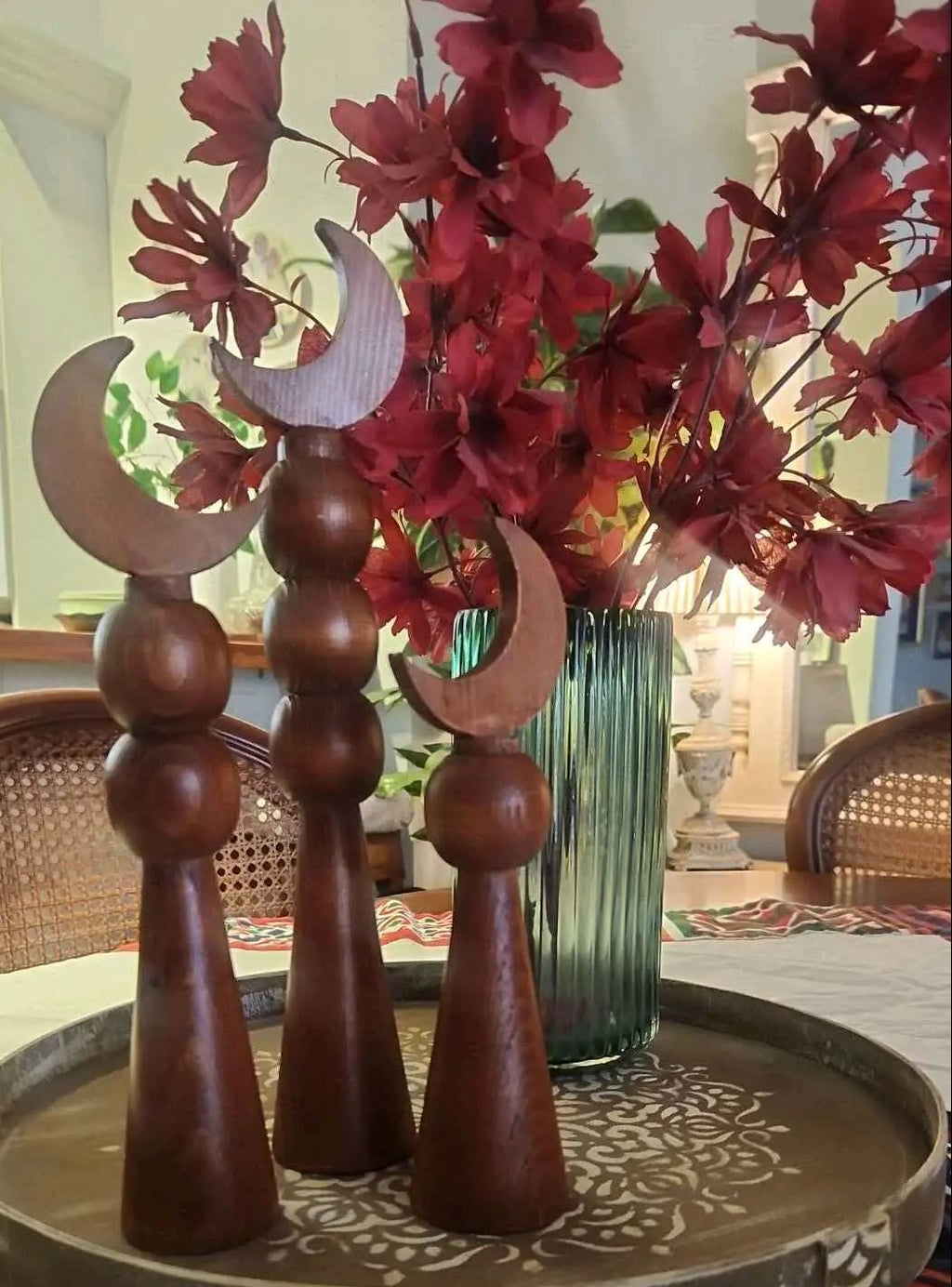 Decorative wooden pieces with a vase of red flowers on a table.