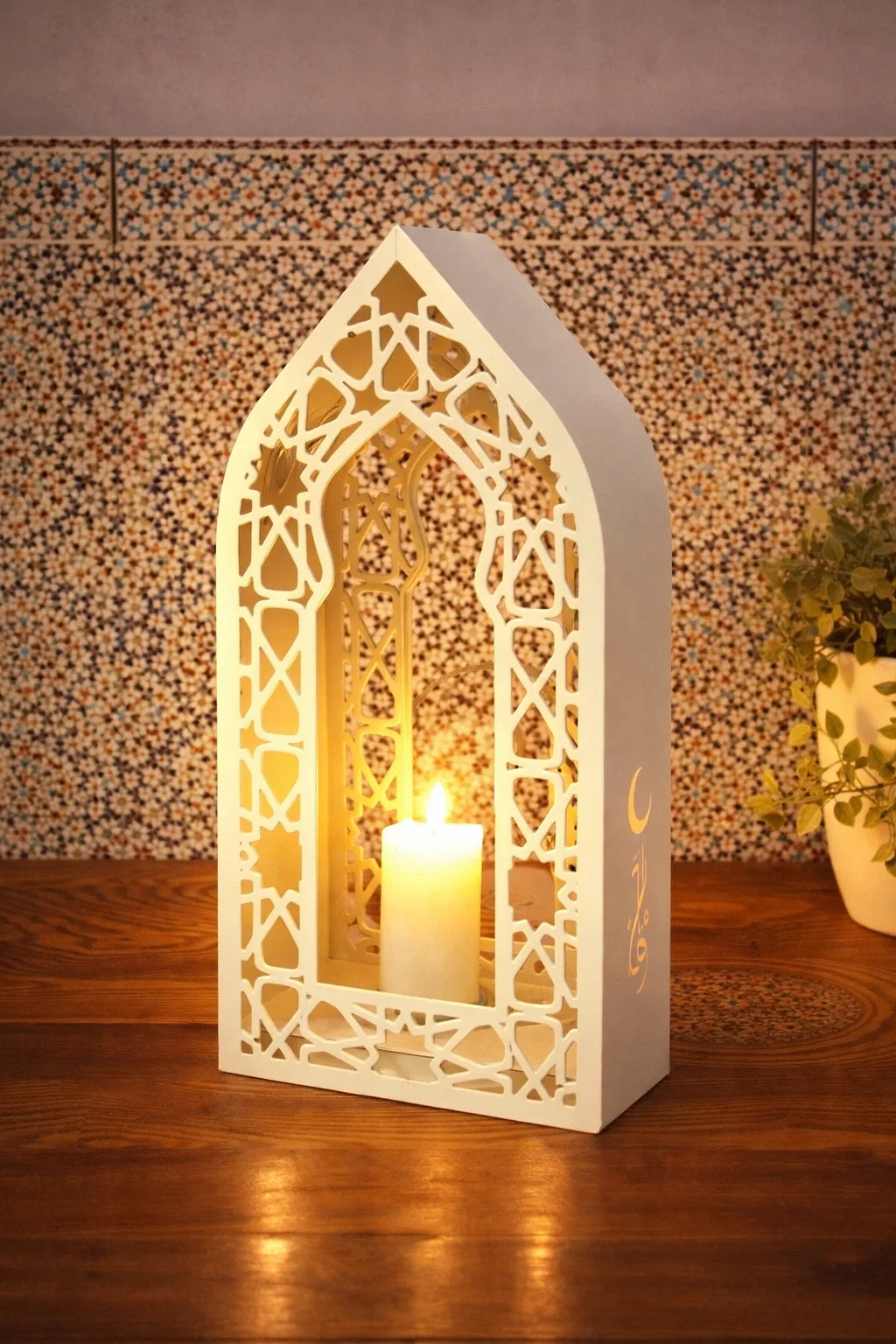 Decorative lantern with a lit candle inside, featuring intricate patterns on a wooden surface.