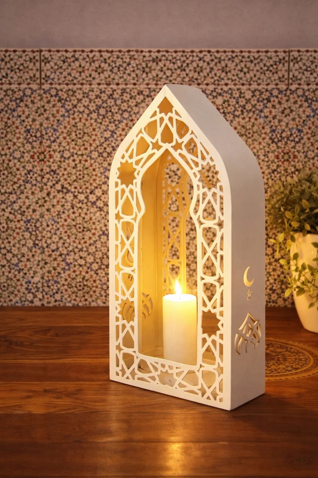 Decorative lantern with a lit candle inside, featuring geometric cutouts on a wooden surface.