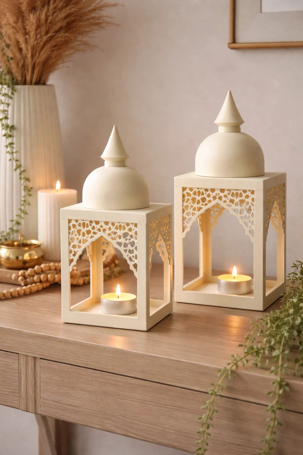 Two decorative lanterns with candles on a wooden surface, surrounded by plants and decor items.