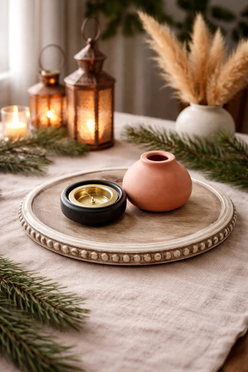 Decorative setting with lanterns, candles, and a pink vase on a wooden tray.