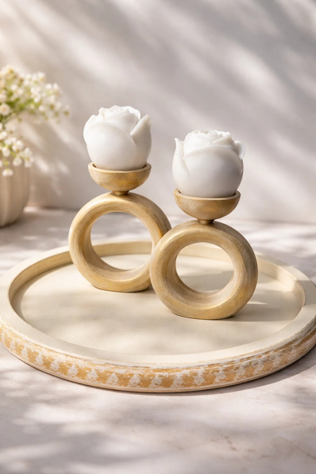 Decorative candle holders with white flowers on a round tray