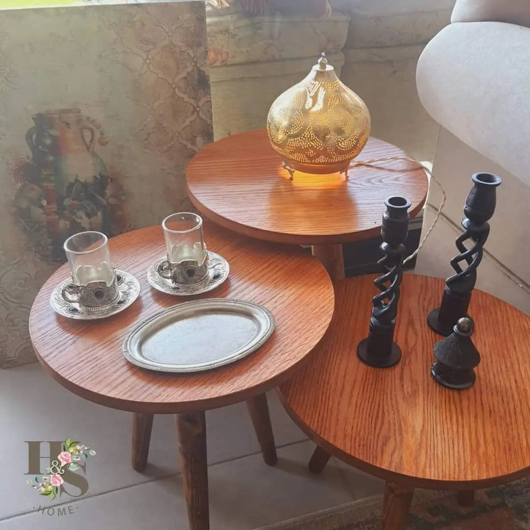 Set of wooden side tables with decorative items including a lamp and candle holders.