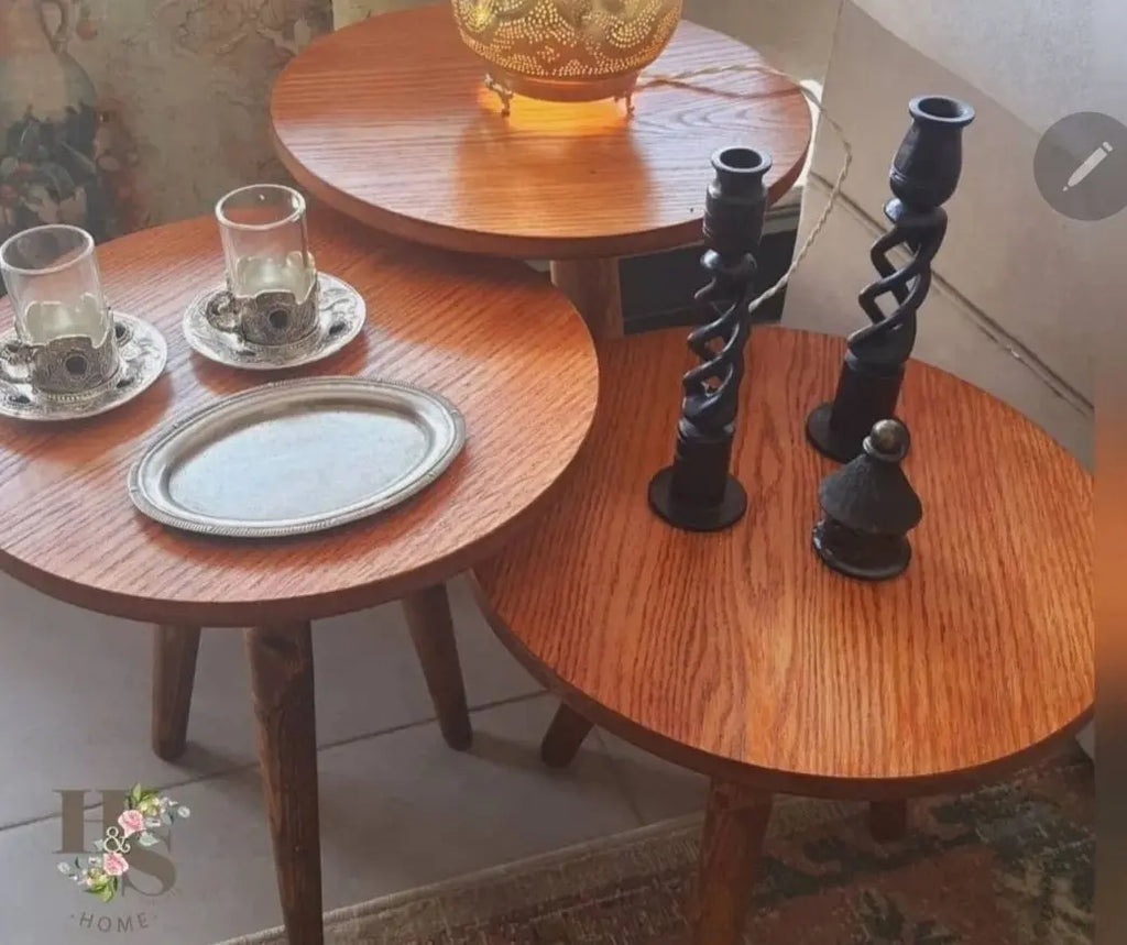 Set of wooden side tables with decorative items on a tiled floor.